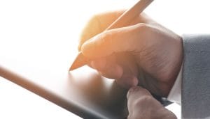 man writing with stylus on tablet