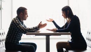 man and women having a serious conversation at a table.
